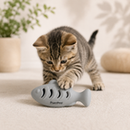 Kitten playing with a blue fish-shaped purrpro cat toy on a light surface.